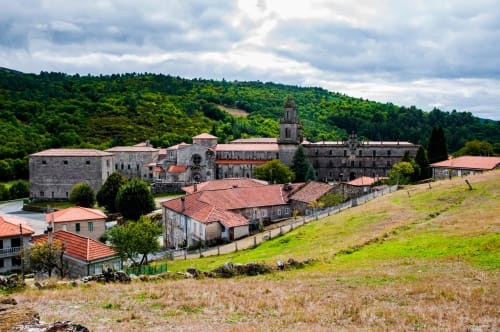 Hotel Casiña D'Avoa en Osera, España con edificios de piedra, tejados de barro cocido, entre verdes colinas y paisaje rural