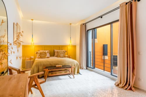 Chambre moderne aux M Résidences et Hôtels avec mur d'accent jaune, luminaires dorés et accès balcon