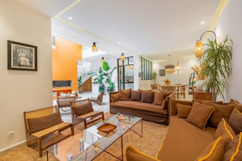 Lounge moderne des Résidences M avec sièges marron, plantes et mur accent cuisine orange en France