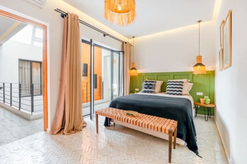 Chambre d'hôtel moderne aux M Résidences avec tête de lit verte, luminaires suspendus et accès à la terrasse