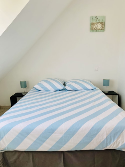 Chambre lumineuse avec literie rayée bleu et blanc, tables de nuit jumelées avec lampes turquoise à Villa Métisse, Groix