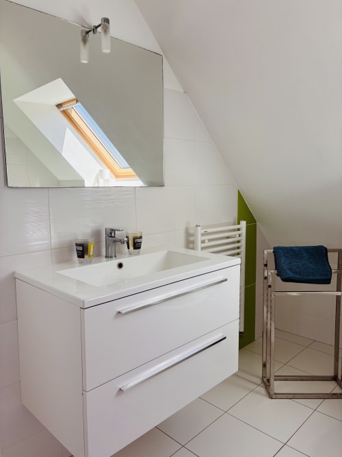Salle de bain moderne avec vasque blanche, miroir et puits de lumière à Villa Métisse, Groix