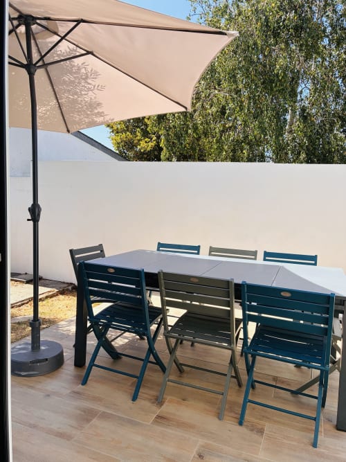 Terrasse de dining extérieure à Villa Métisse à Groix avec table, chaises bleues et parasol cantilever