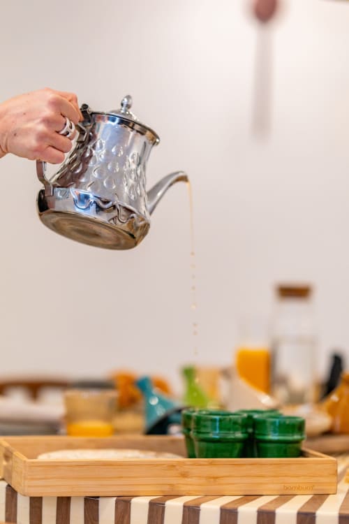 Main versant de l'eau d'une cruche décorée dans la cuisine de M Résidences et Hôtels