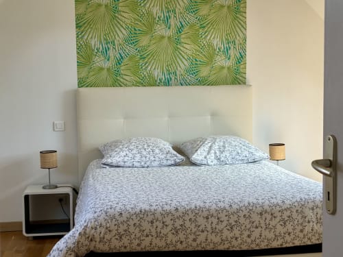 Chambre moderne de la villa Ile et Villas Groix à Groix avec vue mer, tête de lit blanche, literie à motifs et palmier tropical