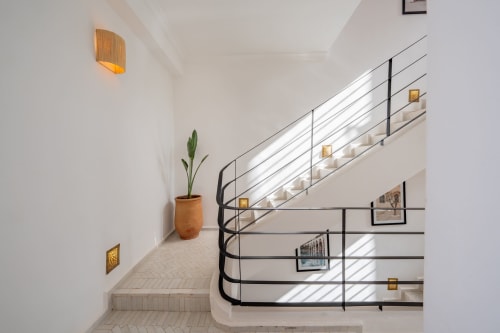Escalier contemporain aux Résidences M avec rampes noires, plante en pot et appliques murales dorées
