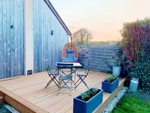 Terrasse en bois avec salon bistro, chaise suspendue et plantes en pot à La Maréchalerie et le Nichoir à Lion en Sullias