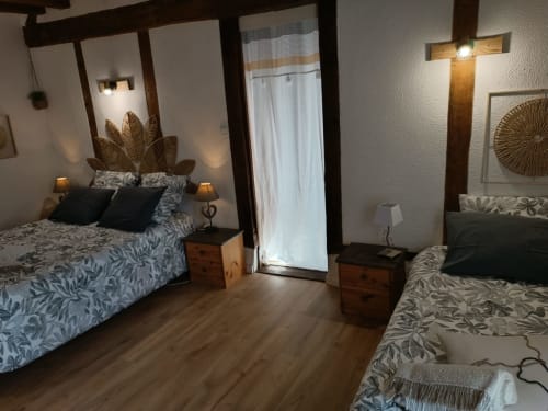 Spacieuse chambre à La Maréchalerie et le Nichoir à Lion en Sulliés avec lits jumeaux, poutres en bois et portes donnant sur le jardin