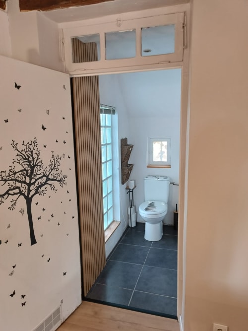 Salle de bain moderne dans la chambre La Forge à La Maréchalerie, Lion en Sullias avec toilettes, fenêtre et décoration murale représentant un arbre