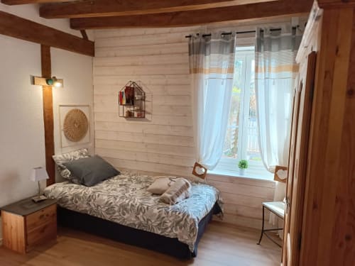 Chambre douillette à La Maréchalerie avec poutres en bois, vue sur le jardin, literie à motifs et décor rustique