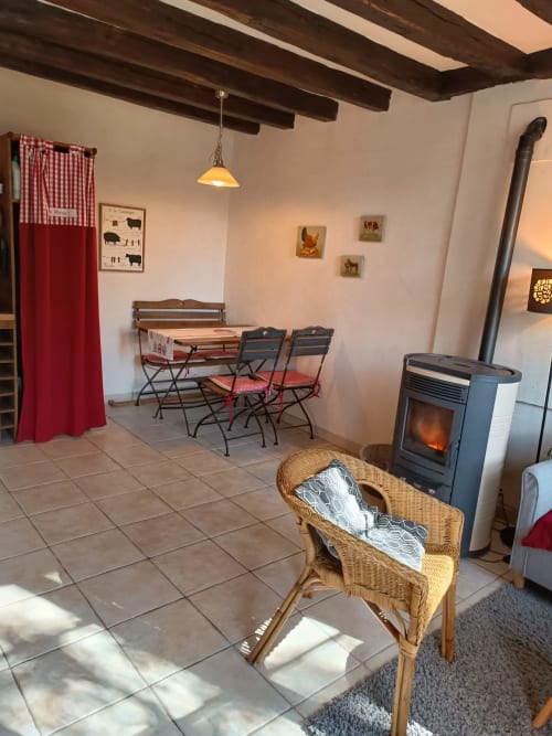 La chambre La Forge à La Maréchalerie et le Nichoir à Lion en Sullias avec cheminée, table à manger et fauteuil en osier