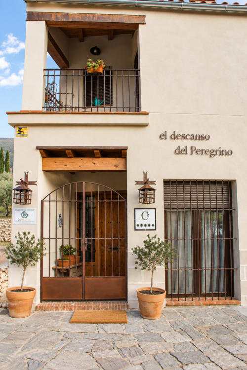 Entrada de El Descanso del Peregrino en Guadalupe, Cáceres con puertas de madera y macetas de terracota