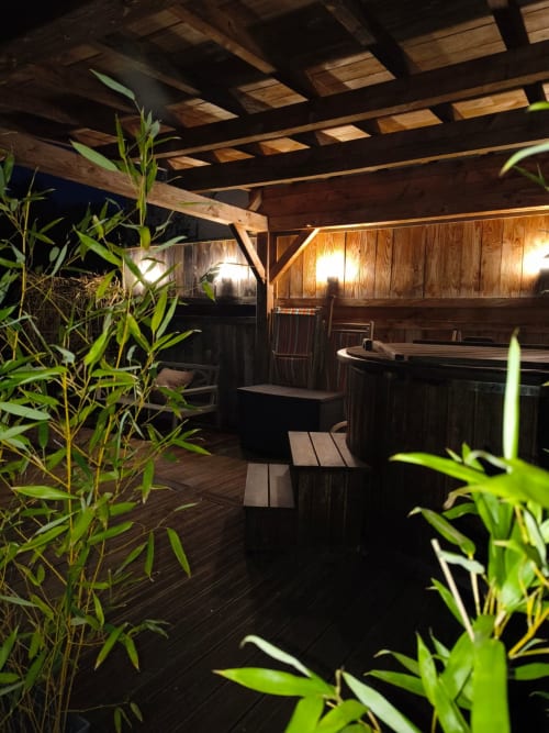 Terrasse pergola en bois la nuit avec plantes de jardin, bain à remous et éclairage chaleureux à La Maréchalerie, Lion en Sullias