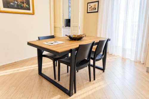 Modern dining area in Sicily In Home apartment with wooden table, black chairs, and bright yellow walls in Catania