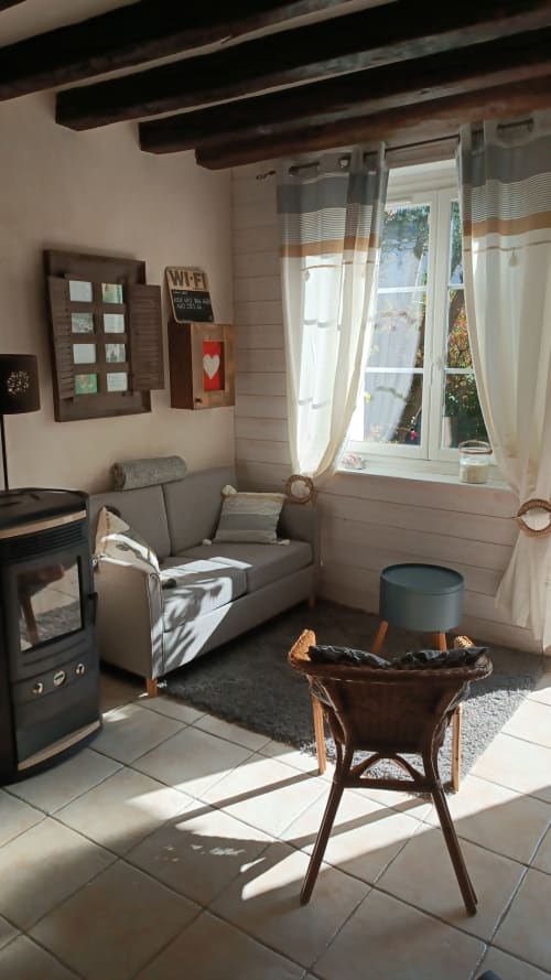 Salon chaleureux à La Maréchalerie et le Nichoir avec cheminée, canapé gris et grande baie vitrée sur Lion en Sullias