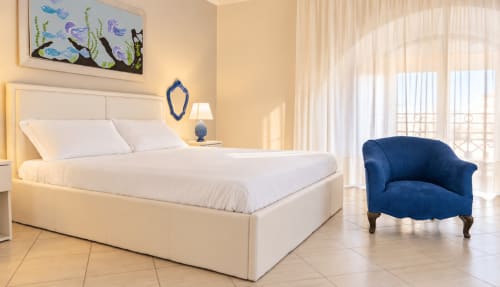 Camera luminosa con letto bianco, poltrona blu e vista sulla città presso Sicily In Home a Catania
