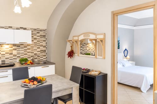 Cucina e zona pranzo moderna dell'appartamento Blue House a Catania, Sicilia con cabinetry bianca, tavolo da pranzo e vista sulla camera