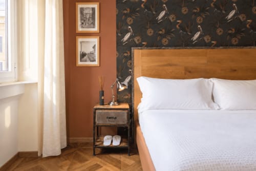 Elegante Camera Doppia Superiore a Porta Tosa Milano con letto in legno, biancheria bianca, pareti color terracotta e carta da parati con motivi floreali scuri