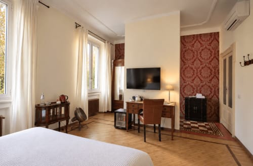 Spaziosa camera Superior a Porta Tosa Milano B&B con letto, TV, scrivania in legno e accenti di carta da parati damascata rossa