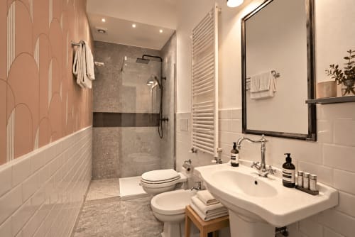 Bagno moderno a Porta Tosa Milano con doccia a filo pavimento, piastrelle bianche, lavabo su colonna e scaldasalviette