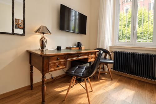 Spazio di lavoro moderno in camera d'hotel a Porta Tosa Milano con scrivania in legno, sedia nera, TV e vista sulla città dalle finestre