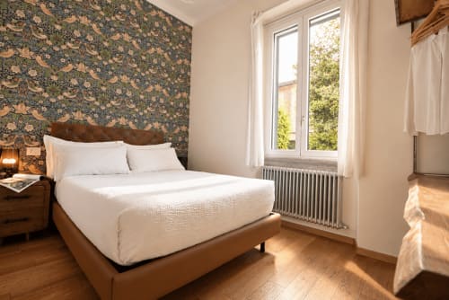 Piccola camera doppia a Porta Tosa Milano con vista giardino, letto in legno, carta da parati floreale e finestre luminose