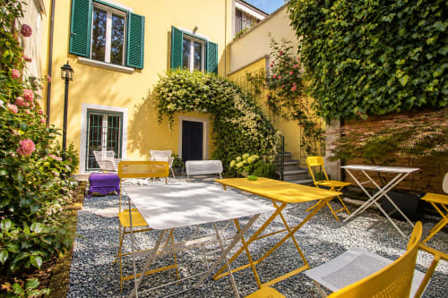 Soleggiata corte della Porta Tosa B&B Milano con lettini gialli, muri ricoperti di edera e piante fiorite