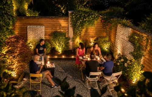 Ospiti che si godono la serata nel suggestivo cortile illuminato di Porta Tosa Milano, circondato da muri ricoperti di edera