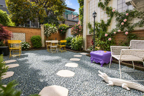 Cortile Porta Tosa a Milano con sedute gialle e bianche, rampicanti fioriti, patio in ghiaia e lastre di calpestio