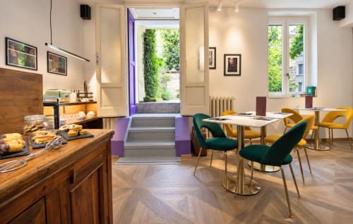 Sala colazione Porta Tosa Milano con tavoli in legno, sedie colorate e vista sul giardino interno verdeggiante
