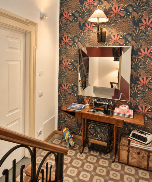 Corridoio Porta Tosa Milano con carta da parati tropicale ornamentale, scrivania in legno, specchio e lampada