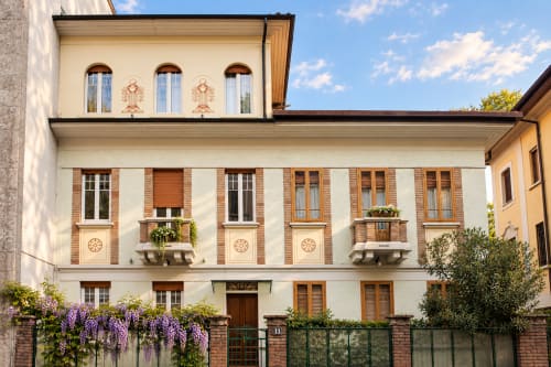 Facciata del Porta Tosa BnB Milano con muri color crema, finestre ad arco, dettagli decorativi e glicine viola