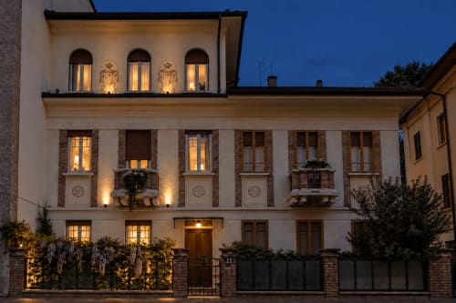 Facciata del Porta Tosa BnB Milano al tramonto, elegante edificio in mattoni con finestre illuminate e aperture ad arco