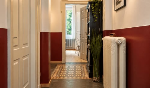 Elegante corridoio di Porta Tosa B&B Milano con pareti rosse, piastrelle ornamentali e porte classiche.
