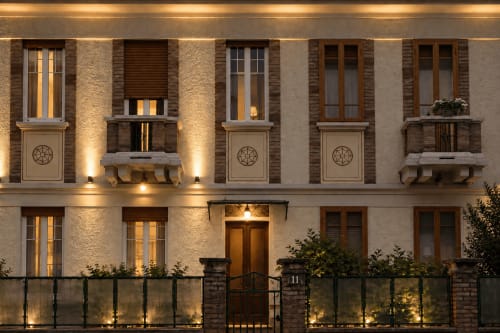 Facciata dell'hotel boutique Porta Tosa di notte a Milano, con mattoni illuminati e eleganti porte in legno