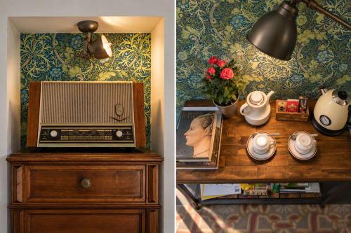 Radio vintage e scrivania in legno presso Porta Tosa B&B Milano, con carta da parati ornamentale, fiori e servizio da tè.