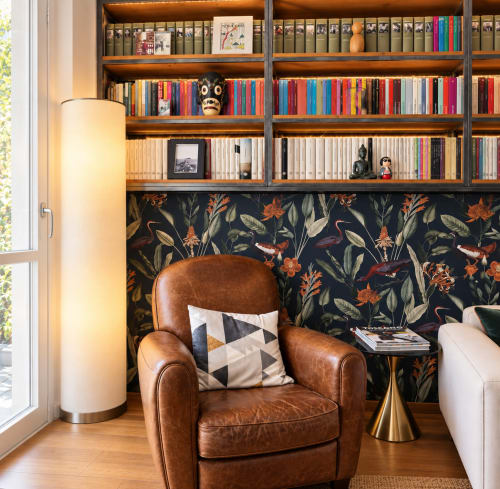 Accogliente angolo lettura a Porta Tosa Milano con poltrona in pelle, librerie integrate e carta da parati botanica