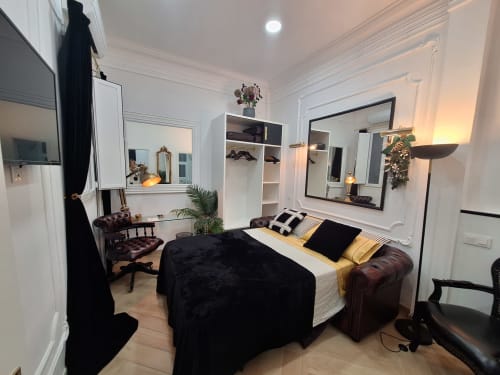 Luxury bedroom at Salamanca Madrid with black bed, gold accents, mirrors, leather seating, and modern amenities