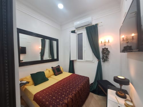 Elegant double bedroom at Salamanca Luxury Rooms Madrid with yellow bedding, black mirror, teal curtains, and ambient