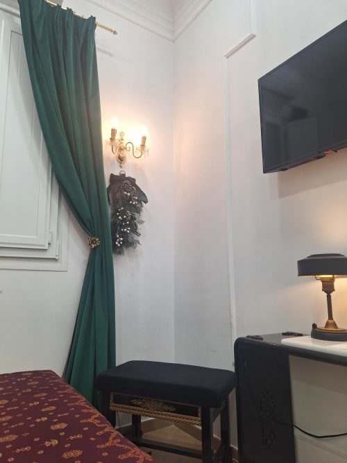 Elegant hotel room at Salamanca Luxury Rooms Madrid with green curtains, wall sconce, flat-screen TV, and classical