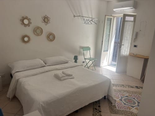 Luminosa camera da letto in stile studio presso Lovelyloft Milano, con letto bianco, decorazioni in vimini e accesso al balcone