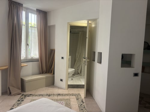 Camera studio moderna a Lovelyloft Milano con finestra, zona salotto, bagno a vista e pavimento con piastrelle decorate