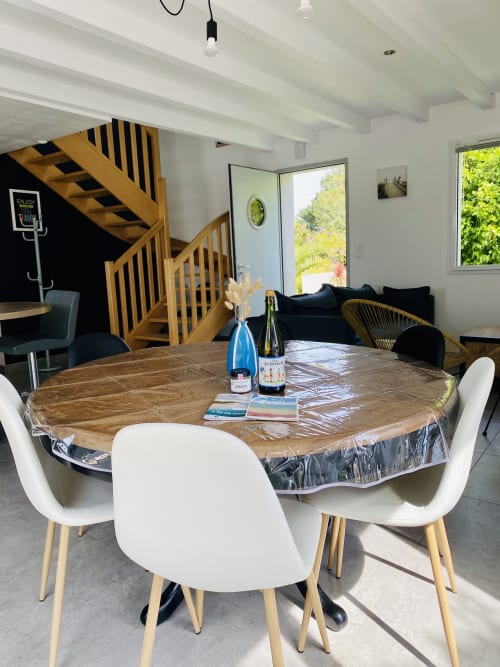 Salle à manger contemporaine à la Villa Métisse à Groix avec table ronde en bois, chaises blanches, vue sur le jardin et la piscine