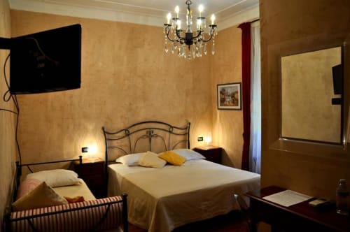 Camera Tripla Standard presso Hotel Villa Moderna a Genova con letto matrimoniale, struttura in ferro battuto, biancheria color crema, texture calda
