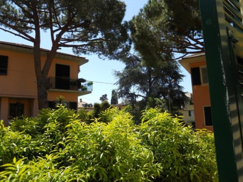 Giardino della corte di Hotel Villa Moderna a Genova con edifici arancioni e rigogliosa vegetazione verde