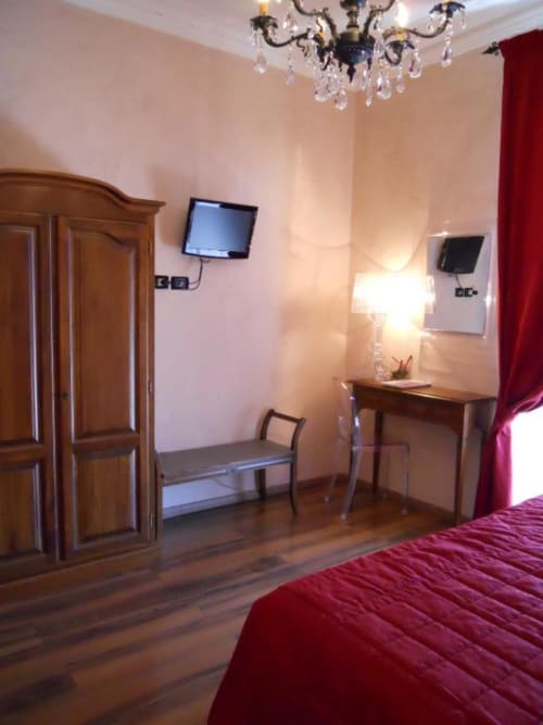 Elegante Suite Deluxe con pavimenti in legno, armadio in legno, scrivania e TV al plasma presso Hotel Villa Moderna di Genova