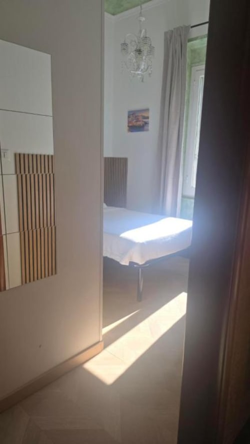 Camera singola standard presso Hotel Villa Moderna a Genova con letto bianco, termosifone, lampadario e vista giardino dalla finestra