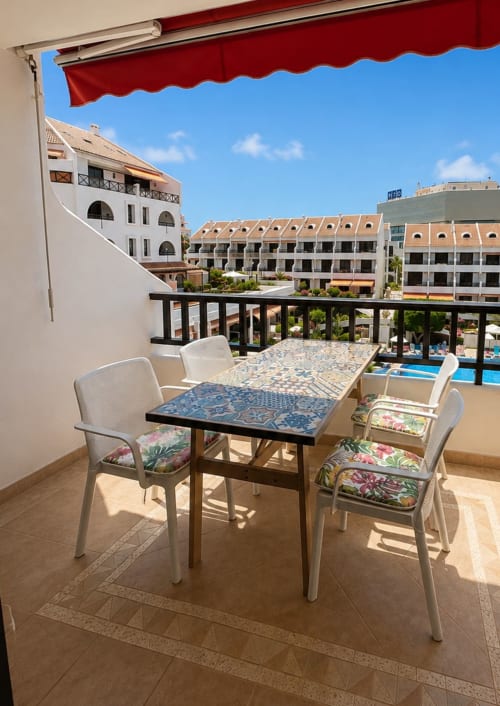 Balcony seating area at Duplex Michelle, Playa de Las Americas, with pool view, dining table, and red awning