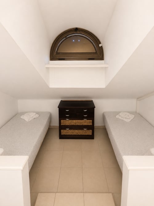 Cozy duplex bedroom with twin beds, dark wooden dresser, and arched skylight window in Playa de Las Americas apartment