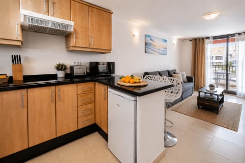 Modern open-plan kitchen and living room in Duplex Michelle apartment, Playa de Las Americas, with wooden cabinets and